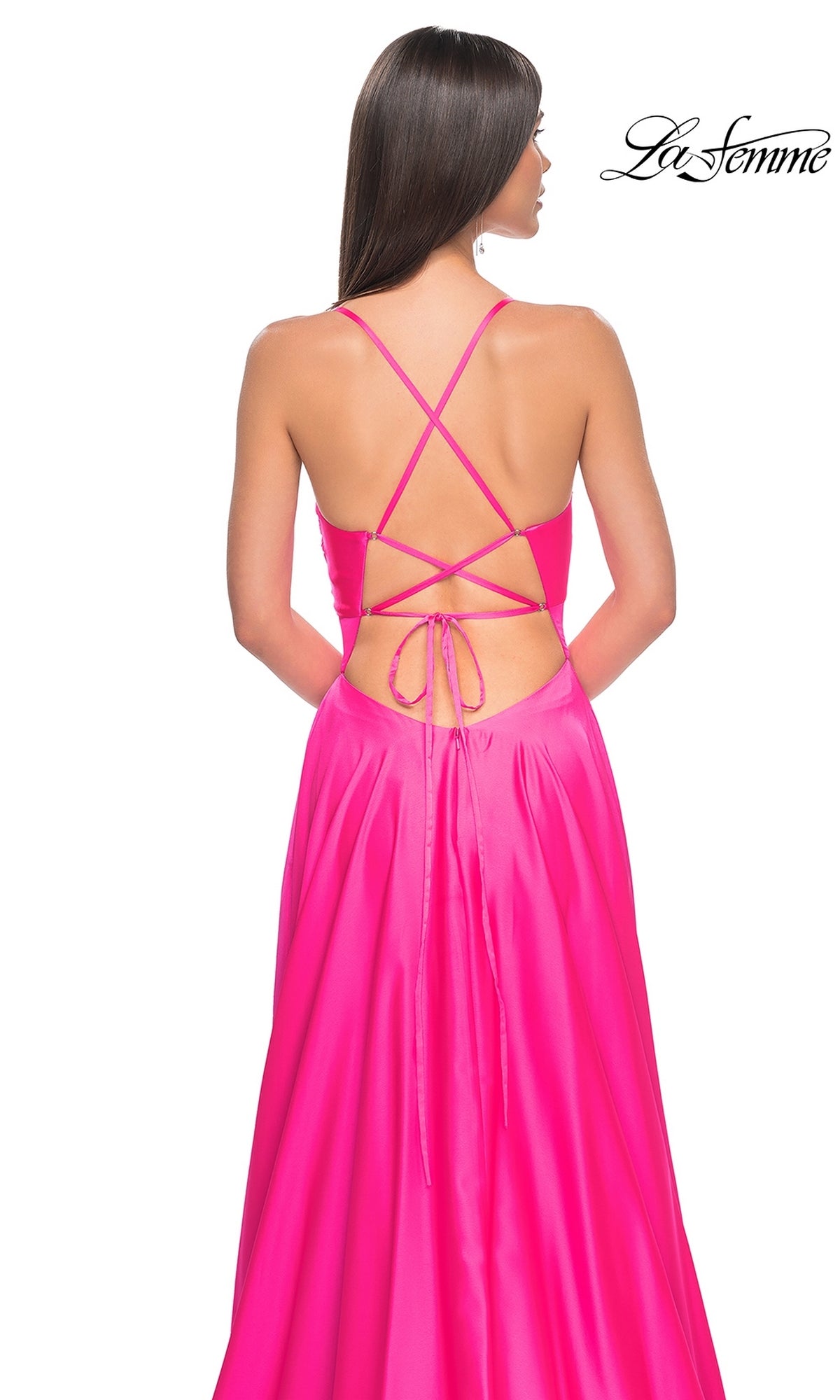 Woman wearing the La Femme Twist-Front Long A-Line Prom Dress 31412, a bright pink satin open-back style with crisscross tie detail, standing against a white background.